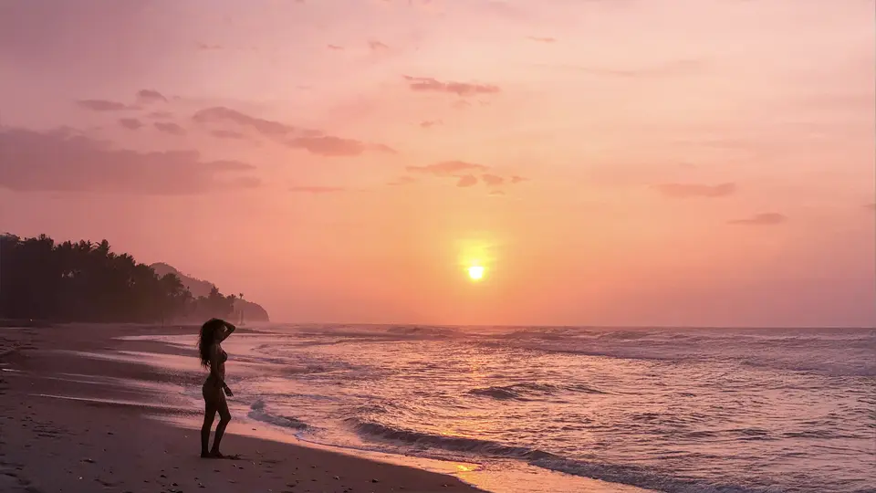 Panoramatický pohled na město Medellín v Kolumbii, pořízený ze svahu v jedné z městských chudinských čtvrtí (slumů); v popředí jsou hustě natěsněné cihlové domky s plechovými střechami rozeseté po zeleném kopci, v pozadí se rozkládá moderní městská zástavba v údolí obklopeném horami, pod částečně zataženou oblohou.